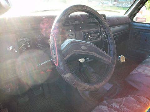 1986 Ford Bronco - The interior of an older truck is shown, focusing on the dashboard, steering wheel, and center console area.