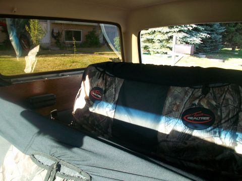 1986 Ford Bronco - Camouflage seat covers are visible inside a vehicle, with a suburban scene seen through the windows.