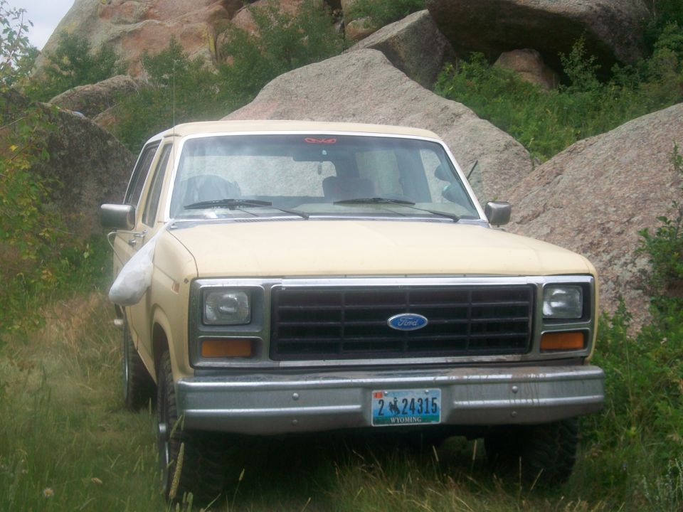 Tan 1986 Ford Bronco front view parked in rocky terrain