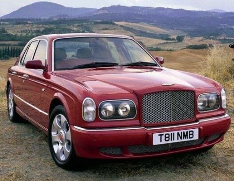 1998 Ford Crown Victoria - This red Bentley Arnage sedan is parked outdoors with a scenic hilly landscape behind it.