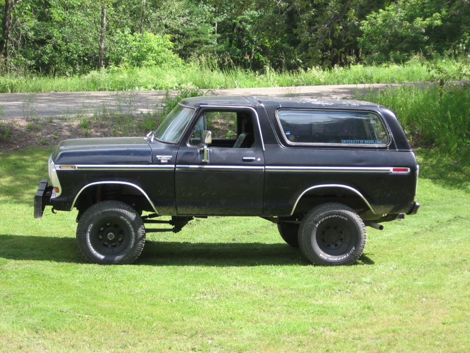 Black 1978 Ford Bronco parked on grass, side view, with chrome trim and BFGoodrich tires