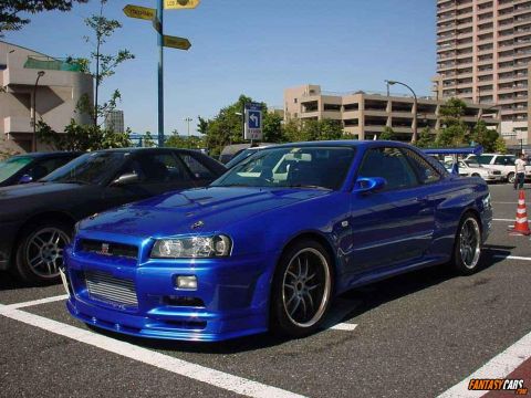 1998 Ford Crown Victoria - A blue sports car with a prominent rear spoiler is parked in a lot.