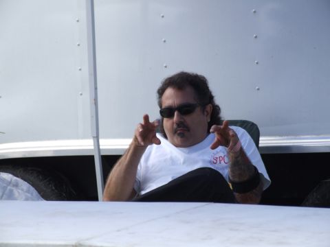 1990 Ford Mustang - A man sits inside a trailer, looking towards the camera with a serious expression and gesturing with his hands.