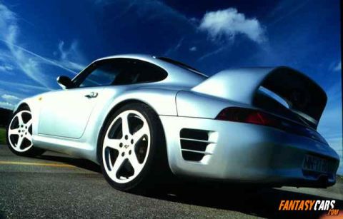 1998 Ford Crown Victoria - Rear view of a silver Porsche 959 sports car with a distinctive rear spoiler and aggressive styling.