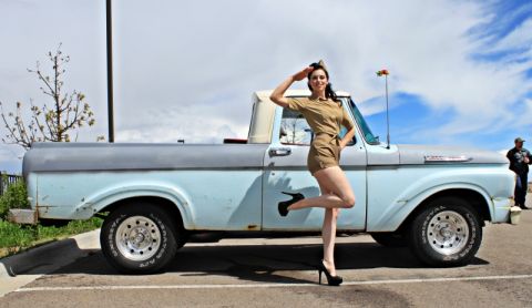 1963 Ford F-100 - A woman in a vintage-style military outfit poses next to a classic light blue and gray 1963 Ford F-100 pickup truck.