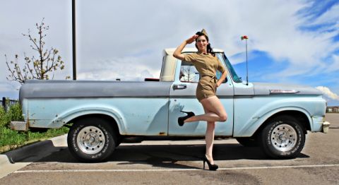 1963 Ford F-100 - A 1963 Ford F-100 pickup truck is parked outside with a woman in a vintage military-style outfit posing.