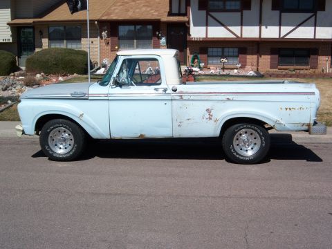 1963 Ford F-100 - Side profile of a light blue 1963 Ford F-100 pickup truck parked on a residential street.