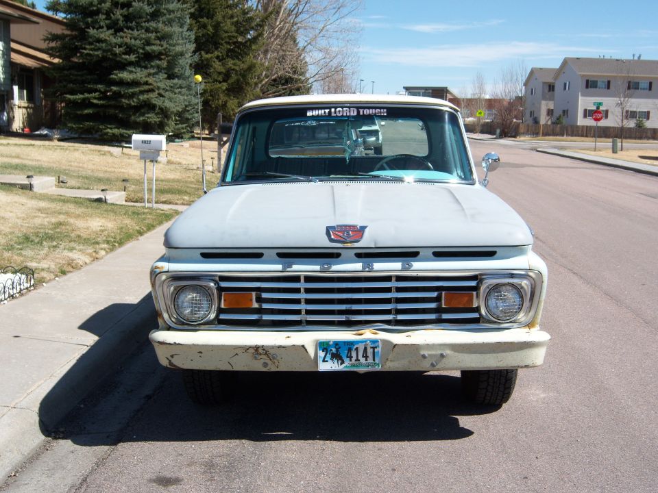 Front view of a light-colored Ford F-series truck with a horizontal grille and round headlights