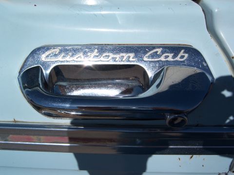 1963 Ford F-100 - Close-up of the "Custom Cab" emblem on a vintage truck door handle.