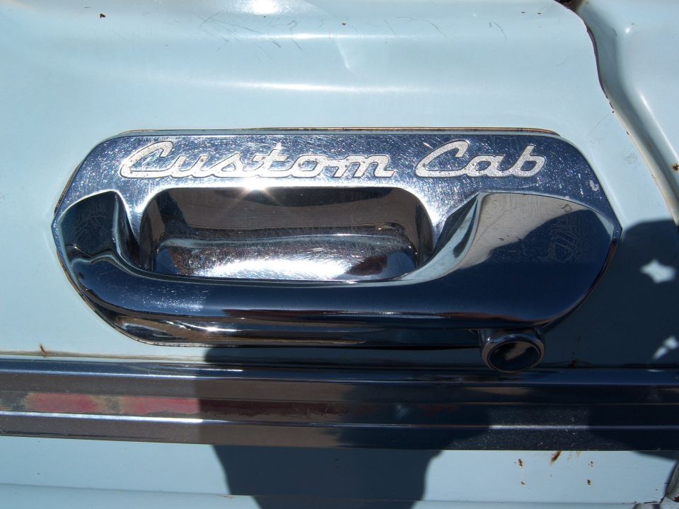 Chrome door handle on a light blue 1963 Ford F-100 with "Custom Cab" text
