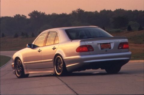 1998 Ford Crown Victoria - Silver sedan with a spoiler and aftermarket wheels is shown from the rear at sunset.
