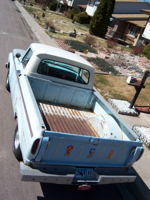 1963 Ford F-100 - This pickup truck has a white camper shell and a faded blue exterior with some rust in the bed.