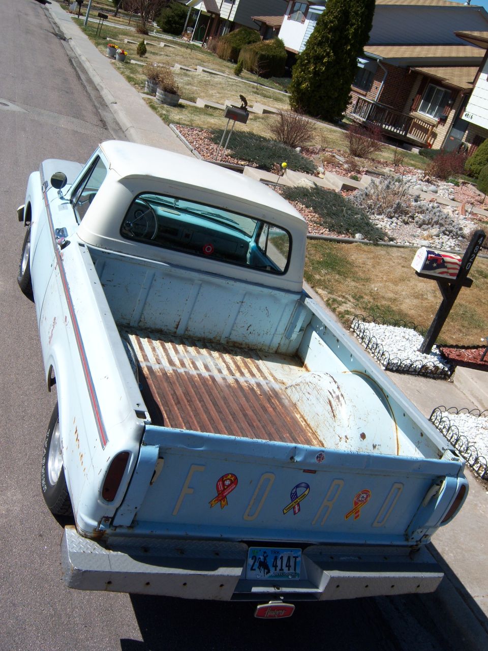 Light blue Ford pickup truck parked on a residential street, rear view