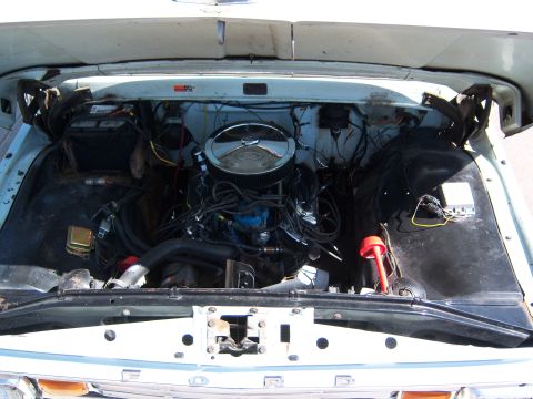 1963 Ford F-100 - The engine bay of a 1963 Ford F-100 pickup truck is shown, a prominent chrome air cleaner and various engine components.