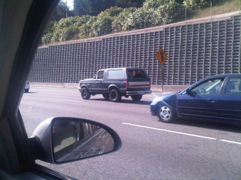 1986 Ford Bronco - A Ford Bronco from the 1980s is seen driving on a highway next to another car.