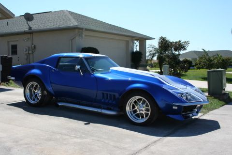 1976 Chevrolet Corvette - A blue 1976 Chevrolet Corvette with white racing stripes is parked in a driveway.