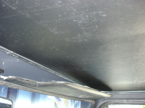 1979 Ford F-250 - The interior headliner of a vehicle shows some wear and dust. A sun visor is visible in the foreground.