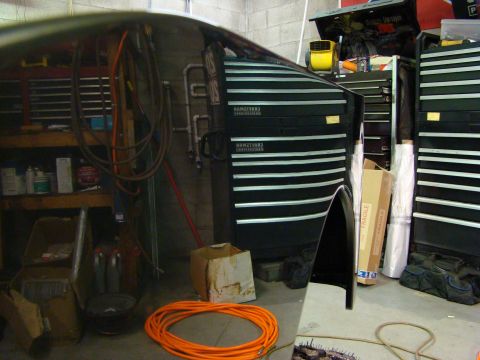 1948 Jeep Wrangler - A black fender and side panel are visible in a garage setting, surrounded by tool chests and equipment.