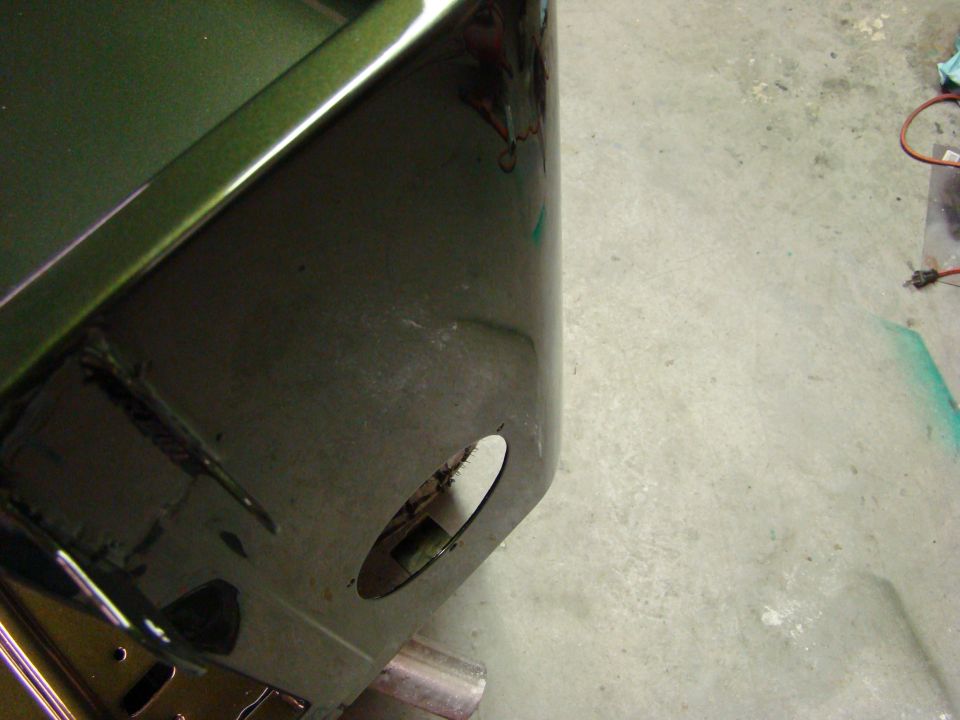 Green vehicle body panel with circular cutout and visible interior components