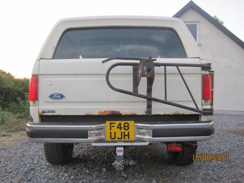 1989 Ford Bronco - Rear view of a white Ford Bronco with a spare tire carrier and a yellow license plate.
