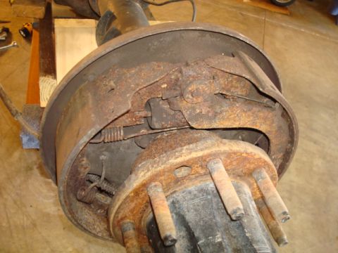 1995 Ford Bronco - Rusty rear axle drum brake assembly showing brake shoes, springs, and hub.