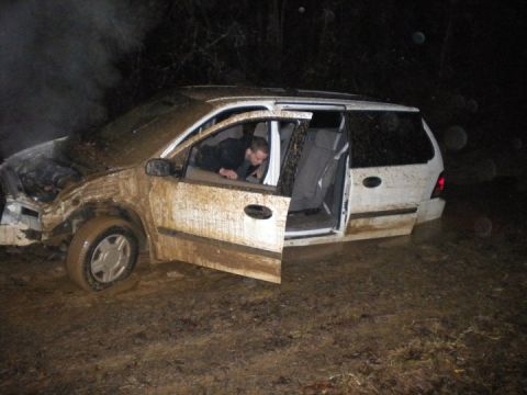 1989 Ford Bronco - A person is inside a mud-covered minivan that is stuck in a muddy area.