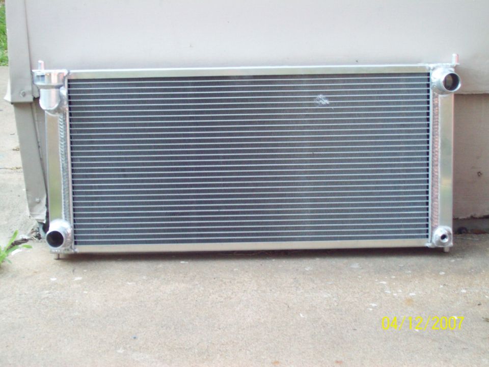 Polished aluminum radiator with welded end tanks standing on a concrete driveway