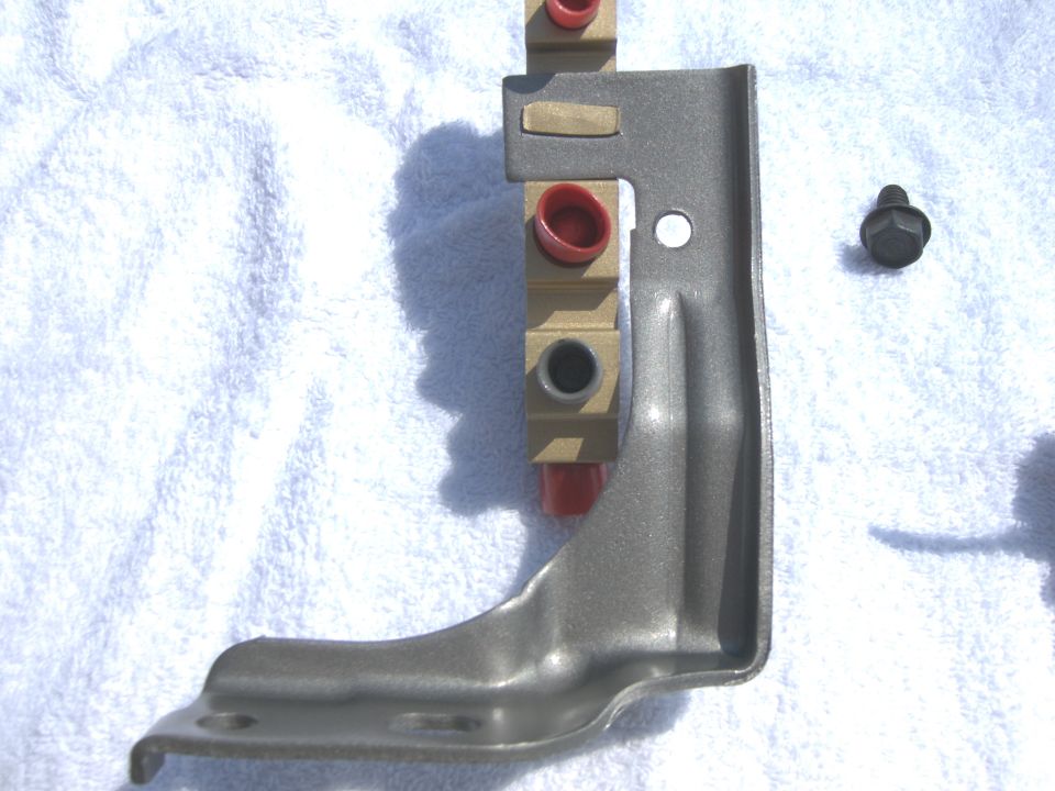Metal bracket with red capped fittings and a bolt on a white towel
