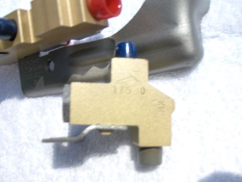 1970 Chevrolet Camaro - Close-up of a brass brake proportioning valve with visible markings and colored caps.