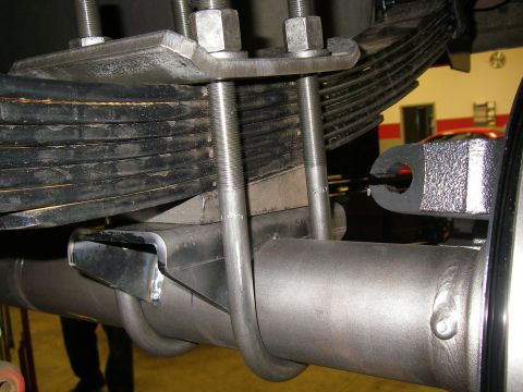 1990 Ford Bronco - Close-up view of a vehicle's rear axle and leaf spring suspension components.