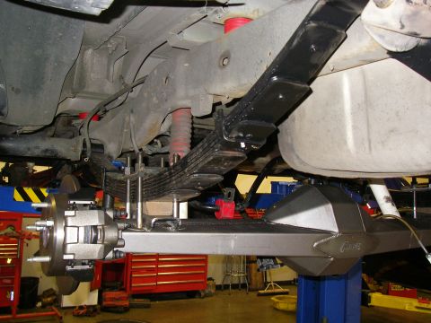 1990 Ford Bronco - Custom rear axle assembly with leaf springs and red shocks visible in a workshop.