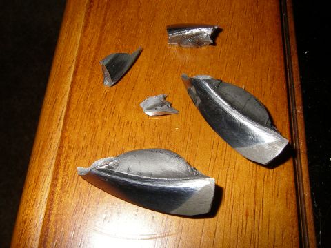 1990 Ford Bronco - Several pieces of damaged metal lie on a wooden table.