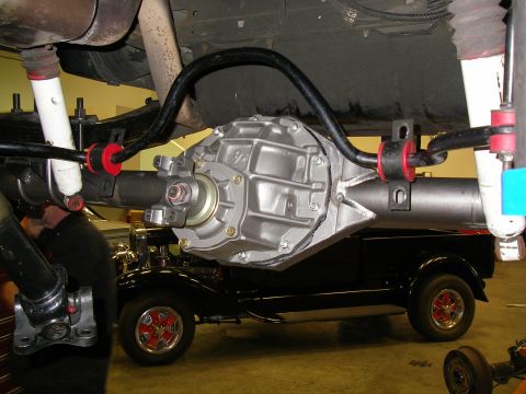 1990 Ford Bronco - Rear axle assembly with Currie F9 differential and sway bar, with a black hot rod visible in the background.