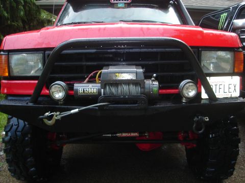 1989 Ford Bronco - Frontal view of a red Ford Bronco equipped with a winch and brush guard.