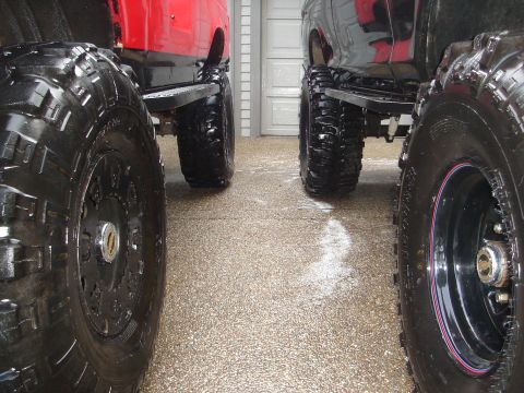 1989 Ford Bronco - Multiple vehicles with large, wet tires are parked in a row, possibly after a wash.