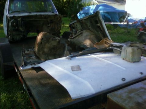 1989 Ford Bronco - Trailer loaded with truck parts and a disassembled chassis, outdoors.