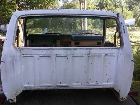 1989 Ford Bronco - Rear view of a white pickup truck cab, revealing the dashboard and bed panels, suggesting a 1980s model.