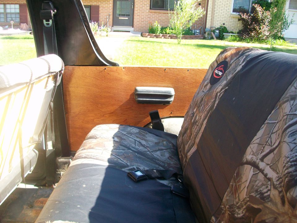 Interior view of a vehicle showing camouflage seat covers and wooden paneling
