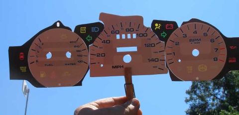 1997 Ford Taurus - Custom gauge cluster with various indicators and readings, held up against the sky.
