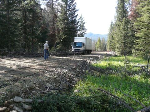 2006 Ford E350 - A box truck is on a dirt road in a wooded area, with a person walking away from the vehicle.
