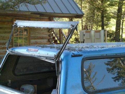 2006 Ford E350 - A blue pickup truck's camper shell appears damaged, with debris scattered across its roof and the shell itself open.