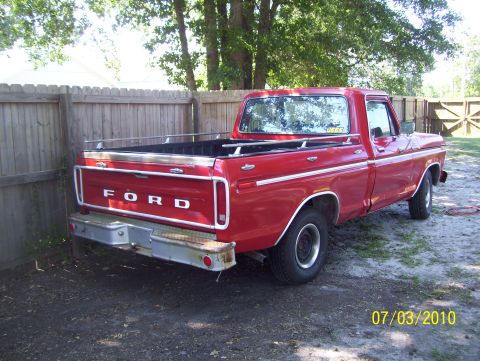 1978 Ford Bronco - Red 1977 Ford F-150 pickup truck parked in a yard with a wooden fence.