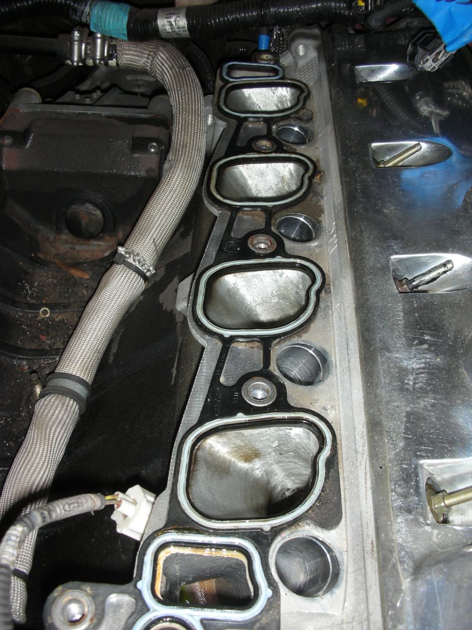 Engine intake manifold gasket with eight ports, showing wear and sealant