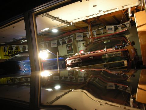 1992 Ford Crown Victoria - Two cars are in a garage, one red and one blue, with Ford Racing banners hanging.