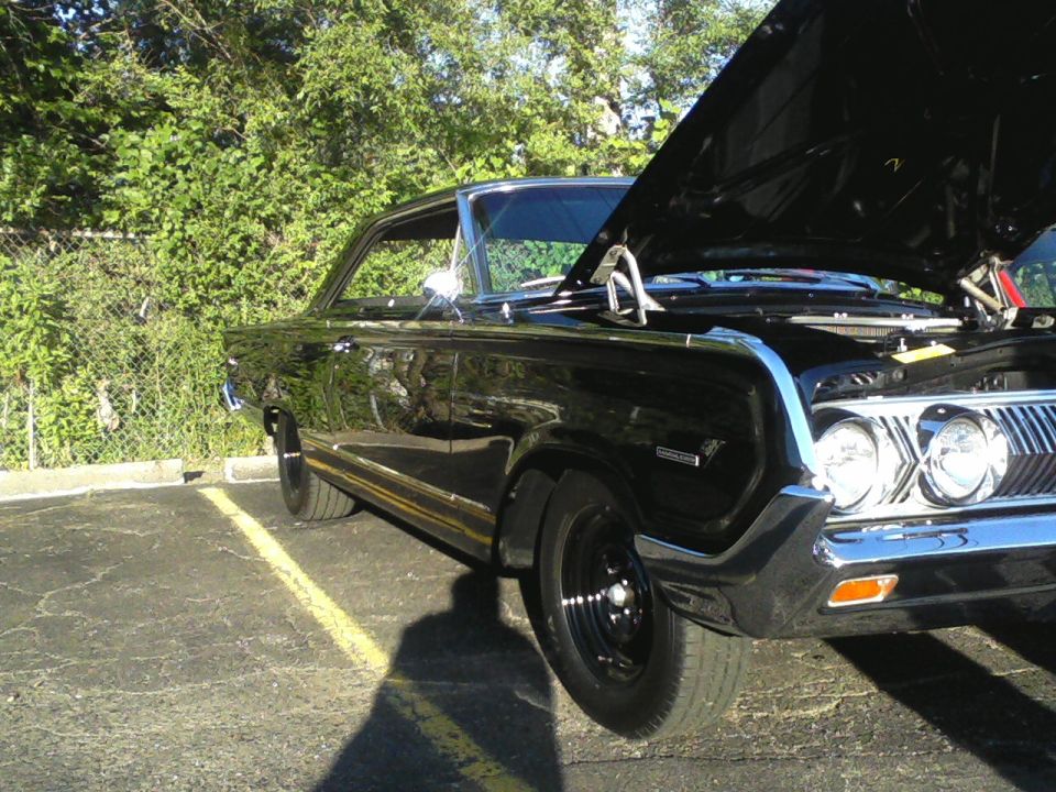 Black 1960s two-door hardtop with hood up, black steel wheels, quad headlights