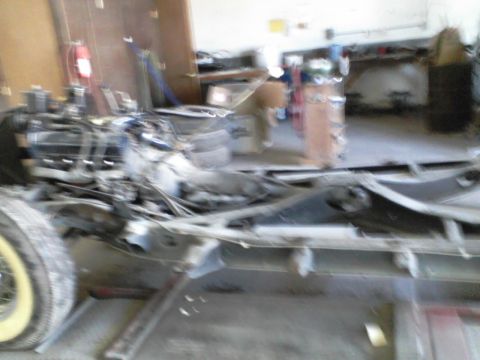 1960 Ford Falcon - The chassis and engine of a vehicle are shown in a workshop environment, with various parts scattered around.