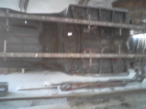 1960 Ford Falcon - The underside of a car chassis is suspended in a workshop, awaiting restoration or repair.