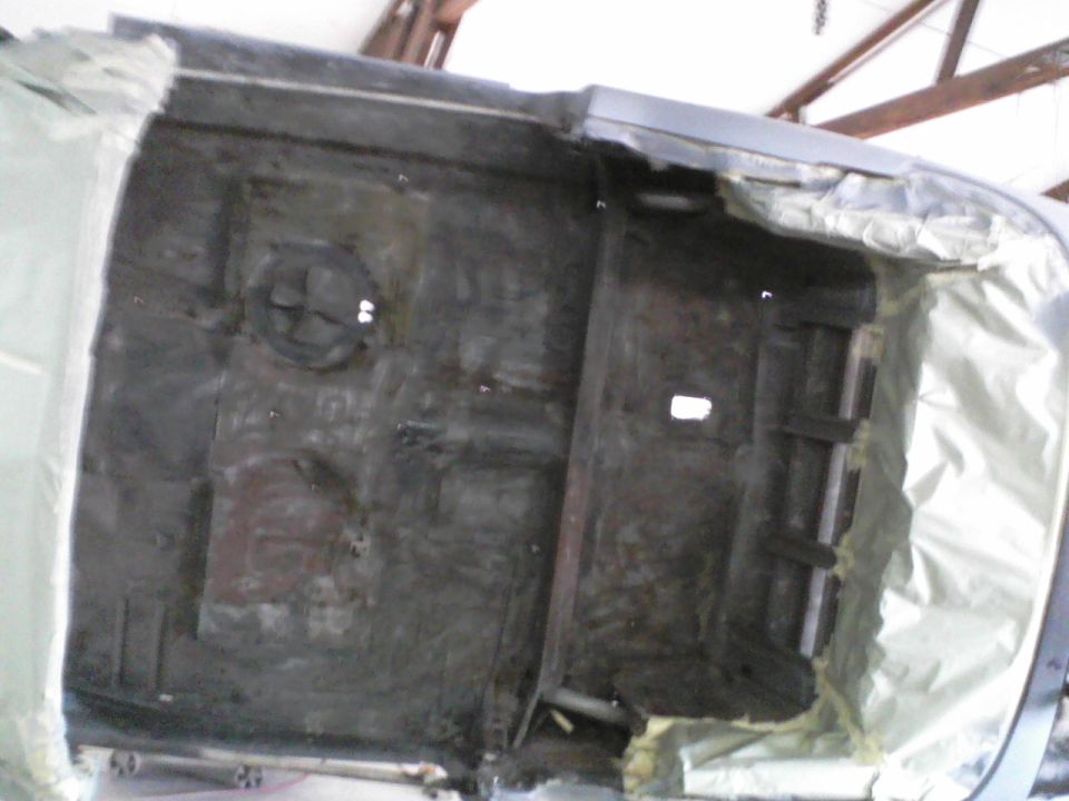 Underside of a car, possibly undergoing restoration, with some parts covered in protective material