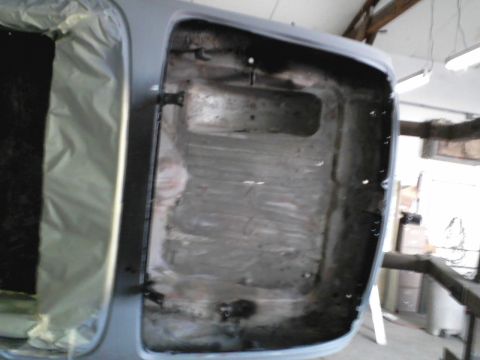 1960 Ford Falcon - The interior of a car trunk shows signs of rust and damage, with protective sheeting on one side.