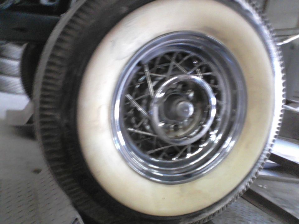 Whitewall tire with a chrome wire wheel. Supermotors.net logo in corner